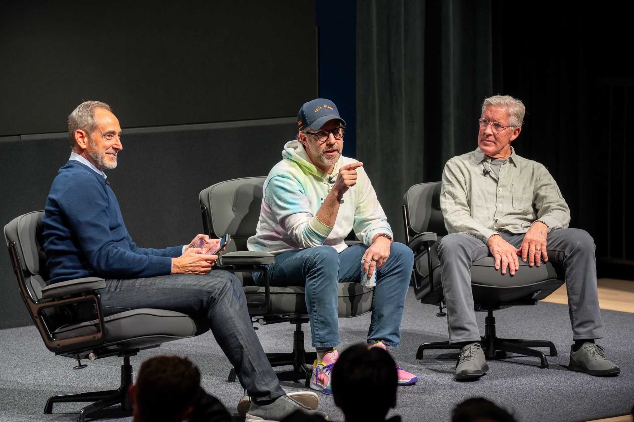 Pete Carroll catching a football on stage in front of his Win Forever pyramid slide